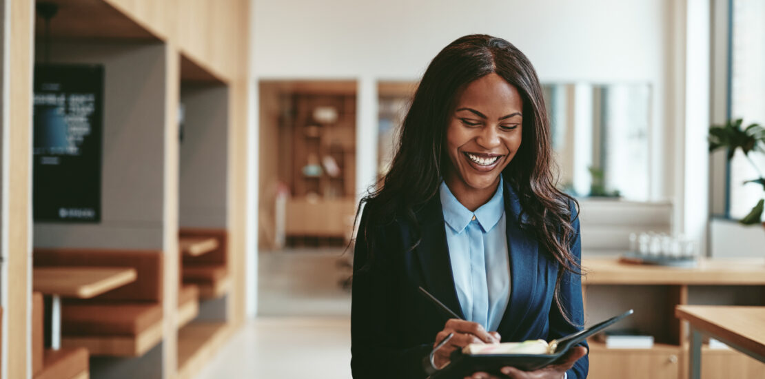 Laughing African American Businesswoman Walking In In Office Writing Notes