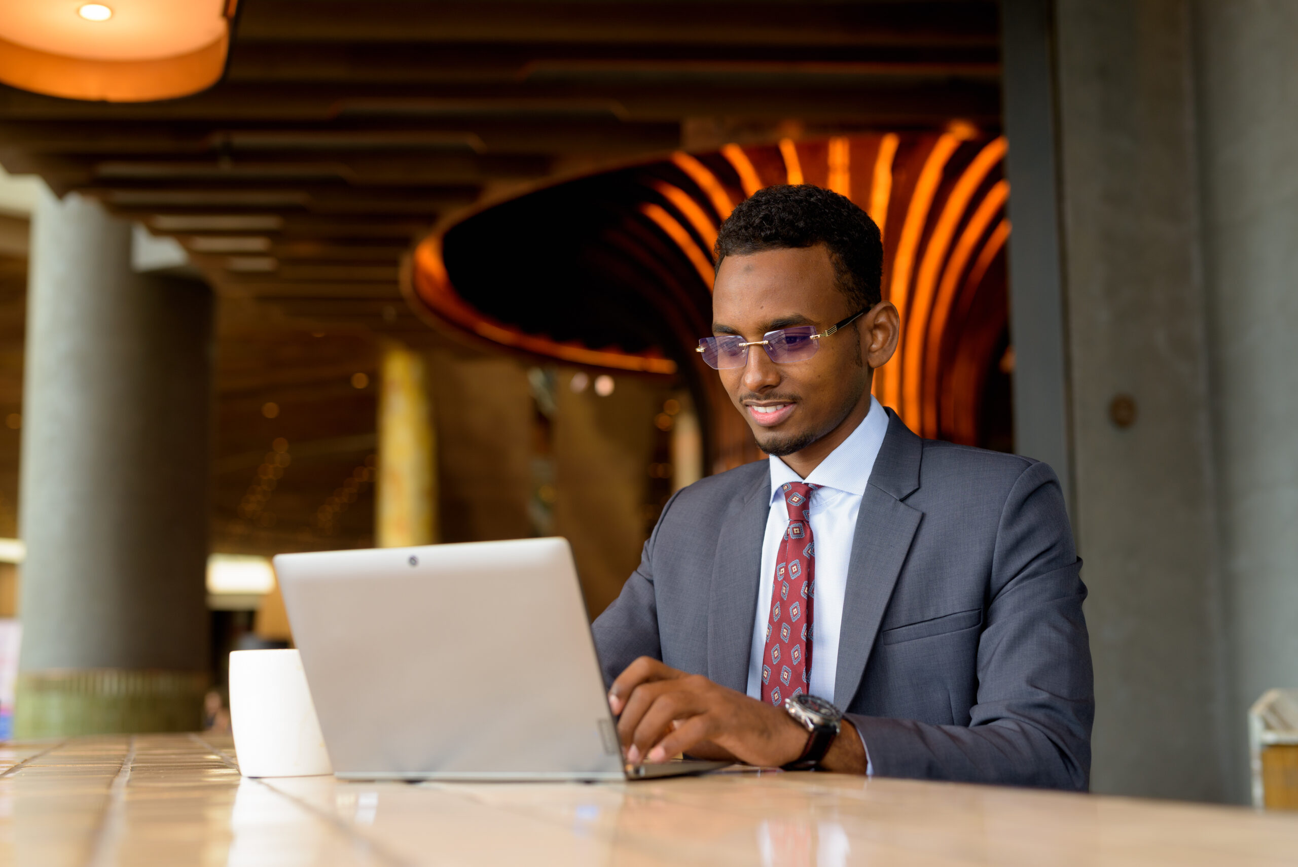 Portrait Of Young African Businessman Wearing Suit And Tie In Coffee Shop