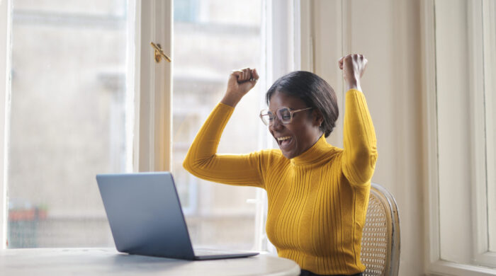 Black Woman Rejoices In Front Of A Computer