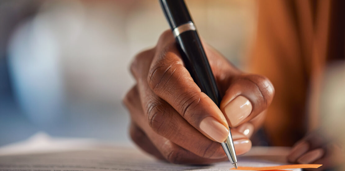 Close Up Of Black Woman Hand Writing On Business Document