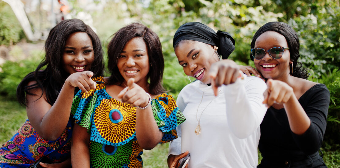 Group Of Four African American Girls Sitting Outdoor And Showing