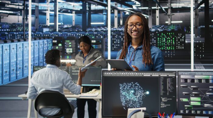 Portrait of upbeat server hub software developer using node tree software to optimize system health. Radiant data center staff member analyzing rigs issues using AI visualization, camera A